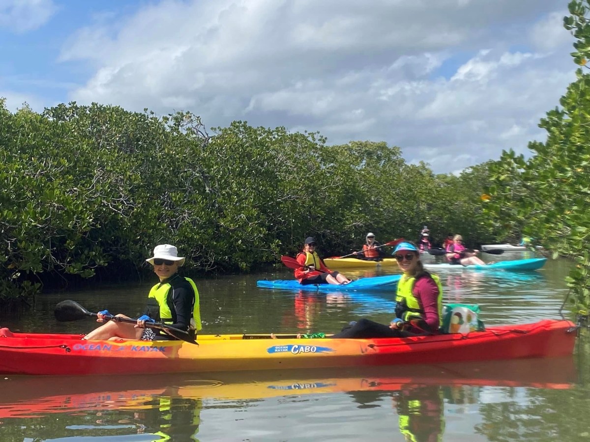 a group of people riding on the back of a boat in the water